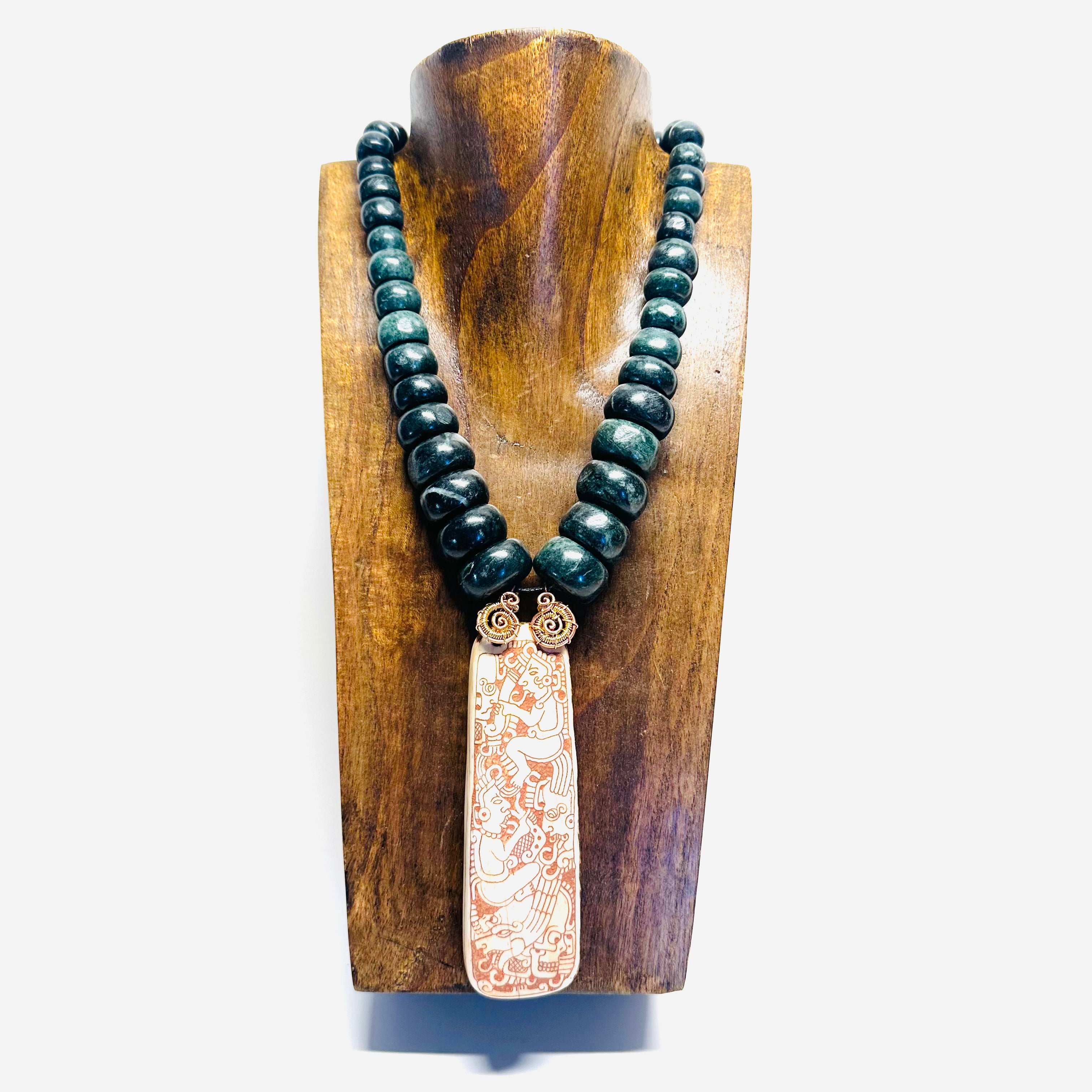 Necklace with dark beads and a decorative pendant on a wooden stand